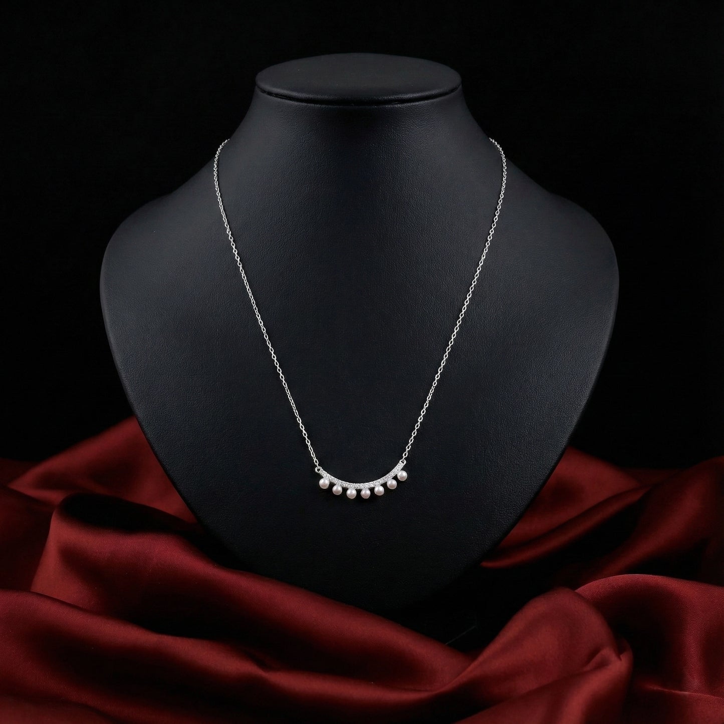 Silver necklace on a black mannequin bust with a red fabric background