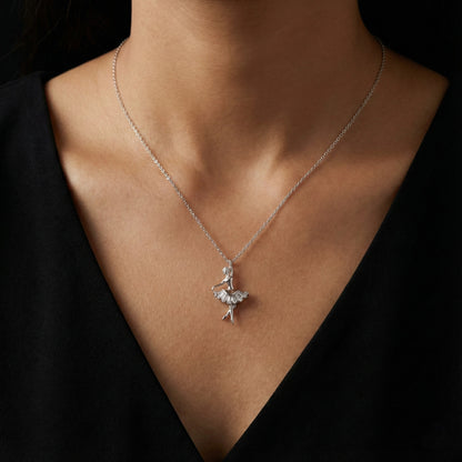 Silver necklace with a delicate pendant on a person wearing a black top.