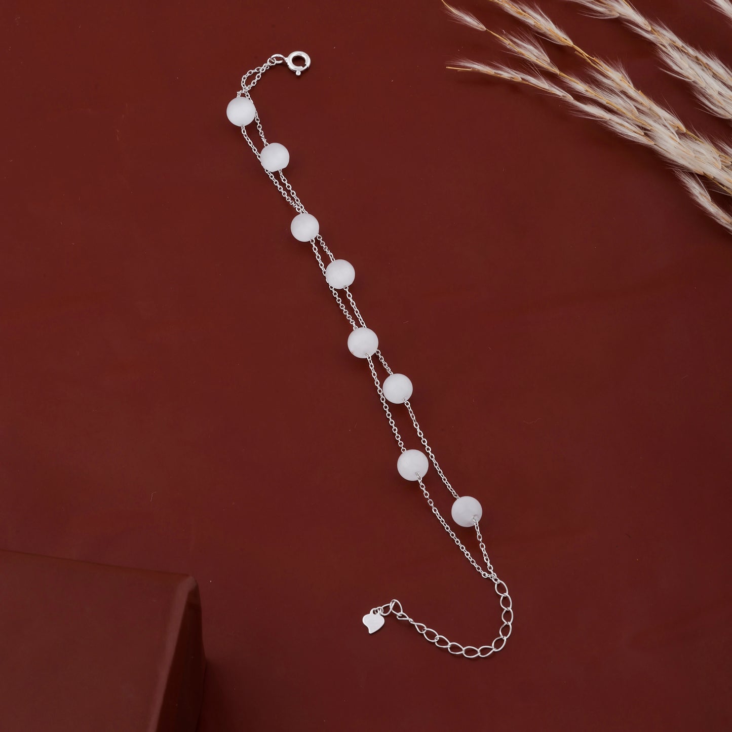 Silver bracelet with white beads on a brown background