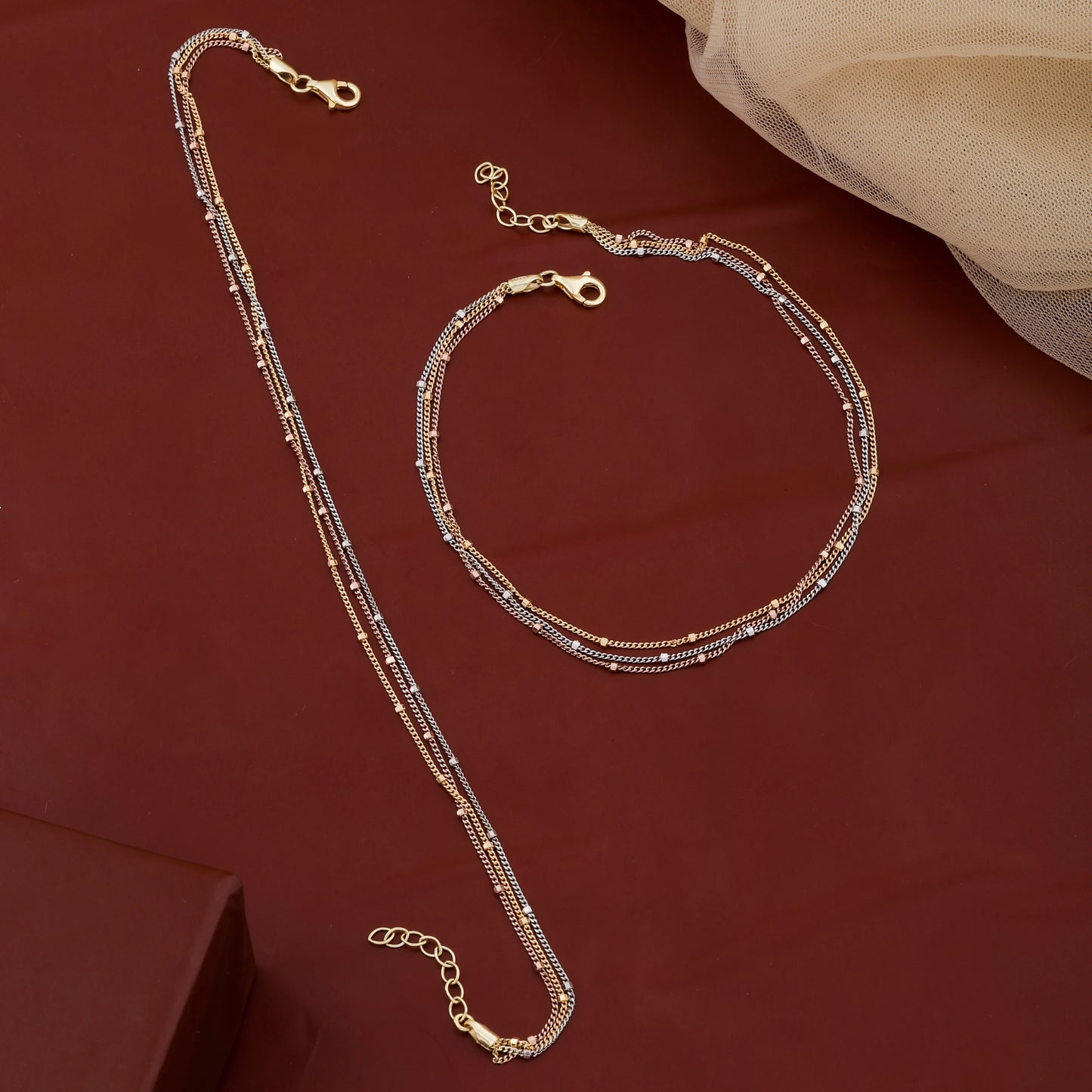 Gold necklace and bracelet set on a red fabric background