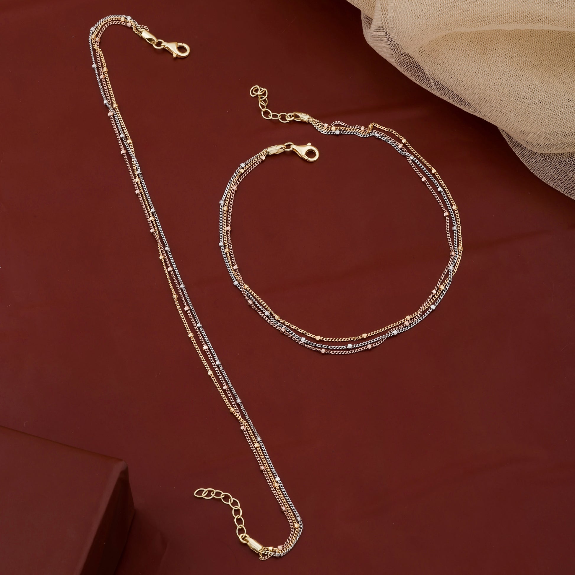 Gold necklace and bracelet set on a red fabric background