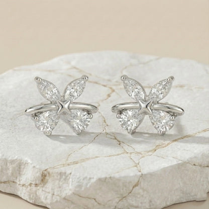 Butterfly-shaped silver rings with clear gemstones on a marble surface