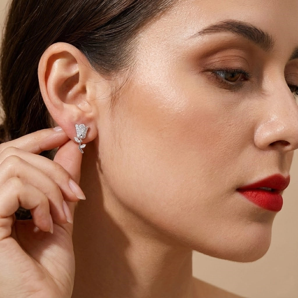 Woman wearing a silver earring with a clear gemstone on a beige background