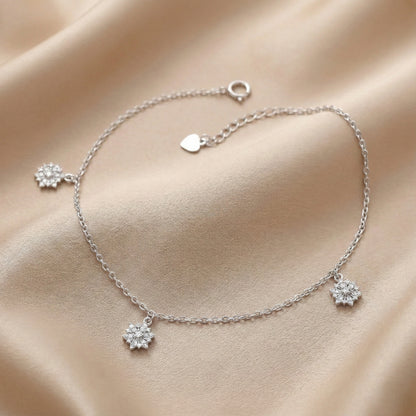 Silver bracelet with floral charms on a beige fabric background