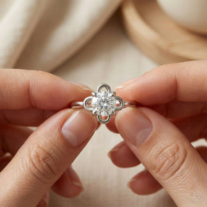 Silver ring with a diamond held between two fingers against a neutral background