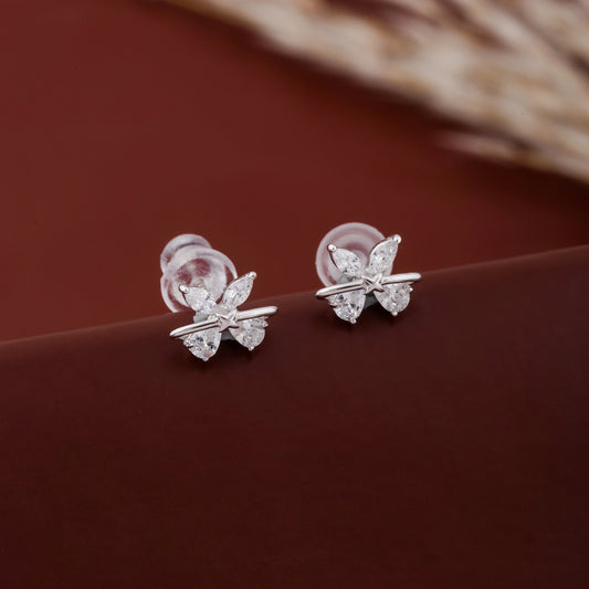 Butterfly-shaped silver earrings on a brown surface