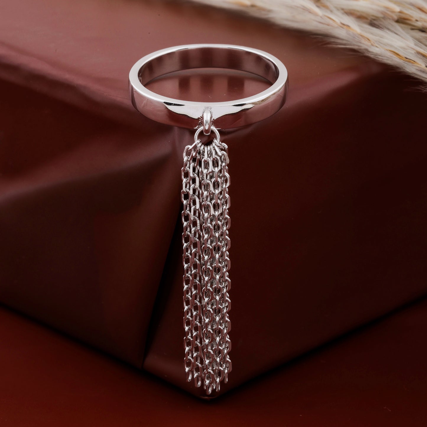 Silver ring with a chain tassel on a brown fabric background