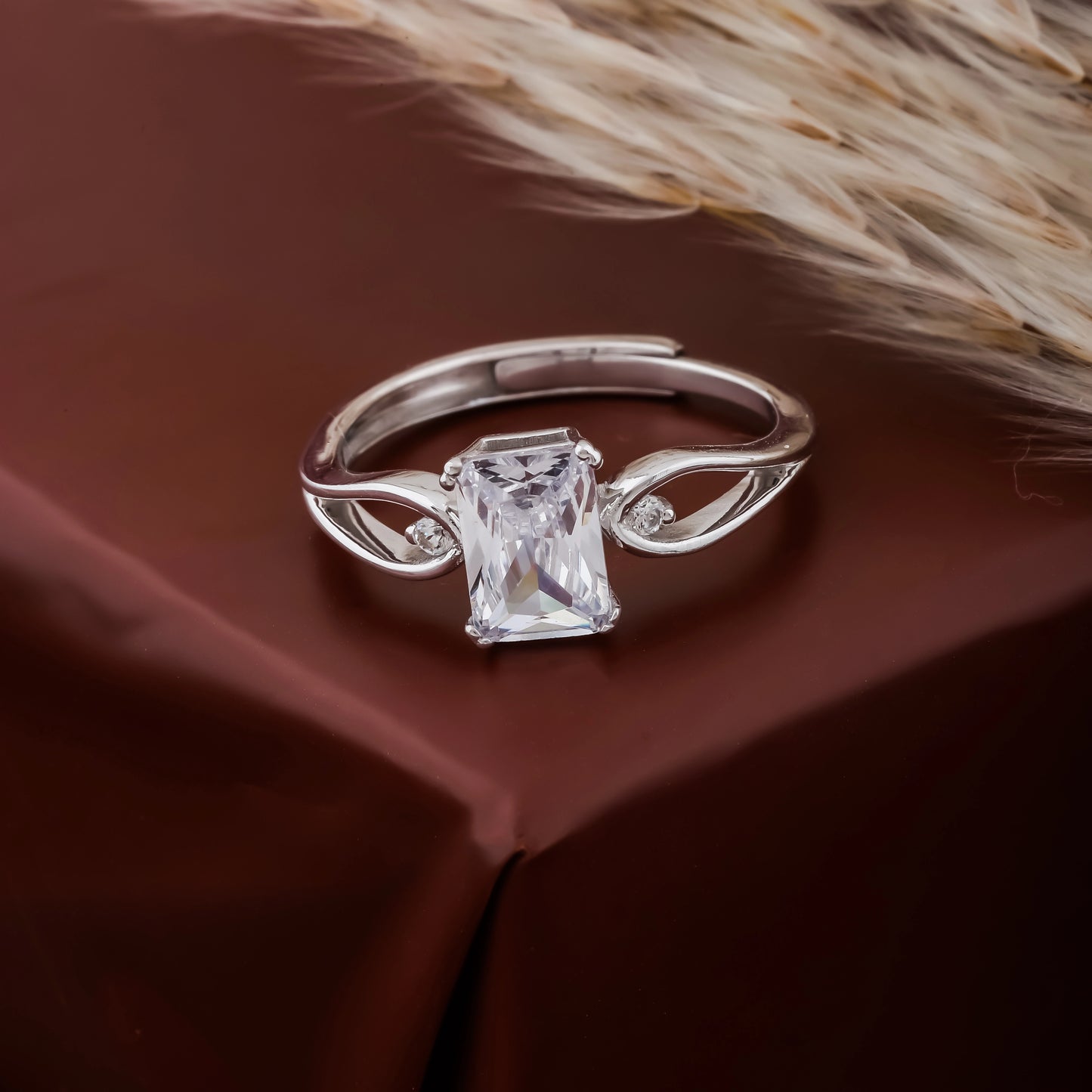 Silver ring with a large rectangular gemstone on a brown fabric background