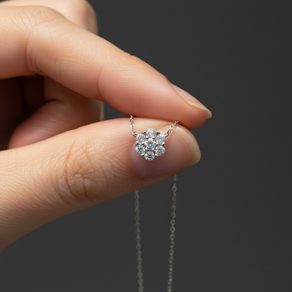 Silver necklace with a diamond pendant held by a hand against a dark background
