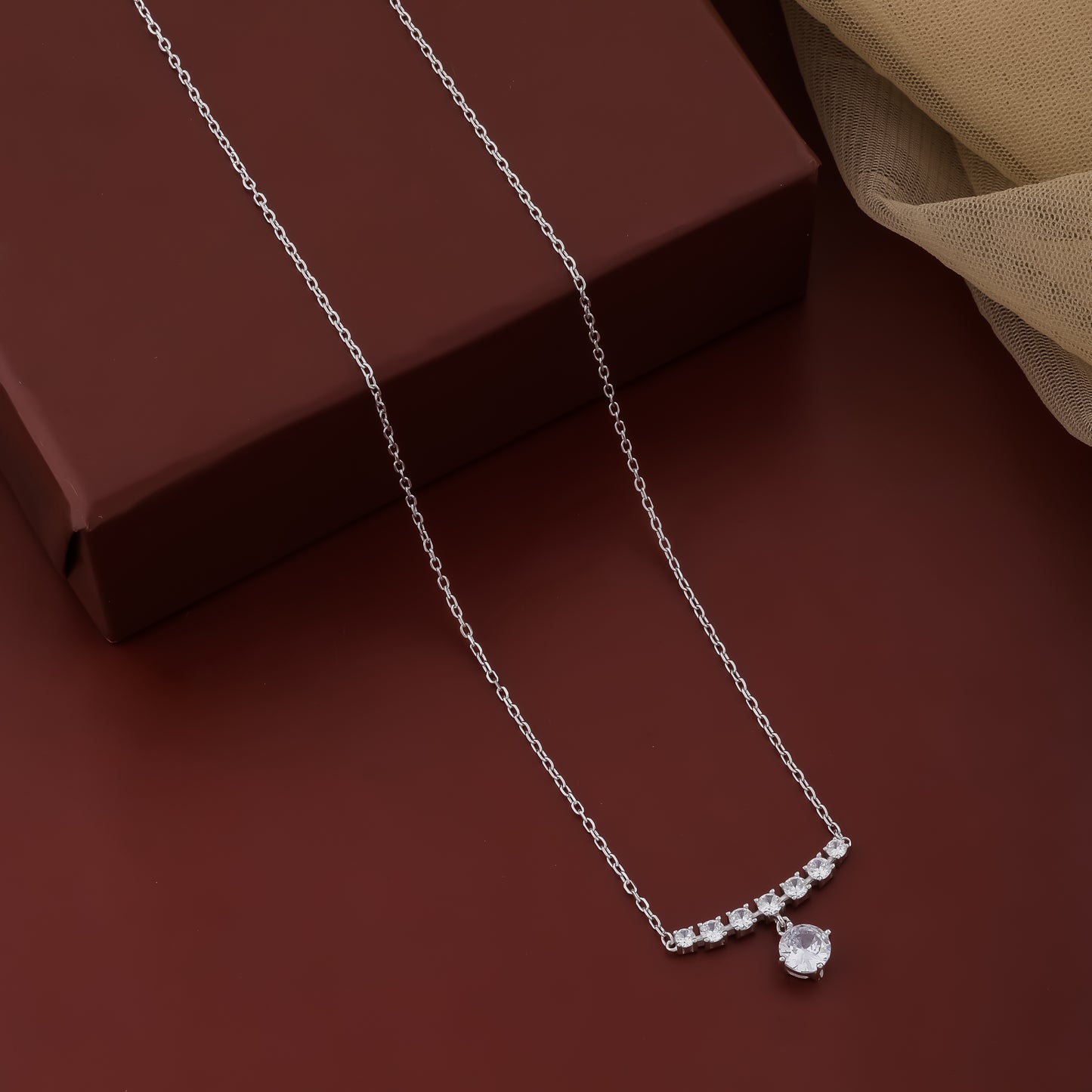 Silver necklace with a pendant on a brown surface