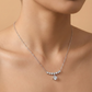 Silver necklace with a pendant on a person's neck against a beige background