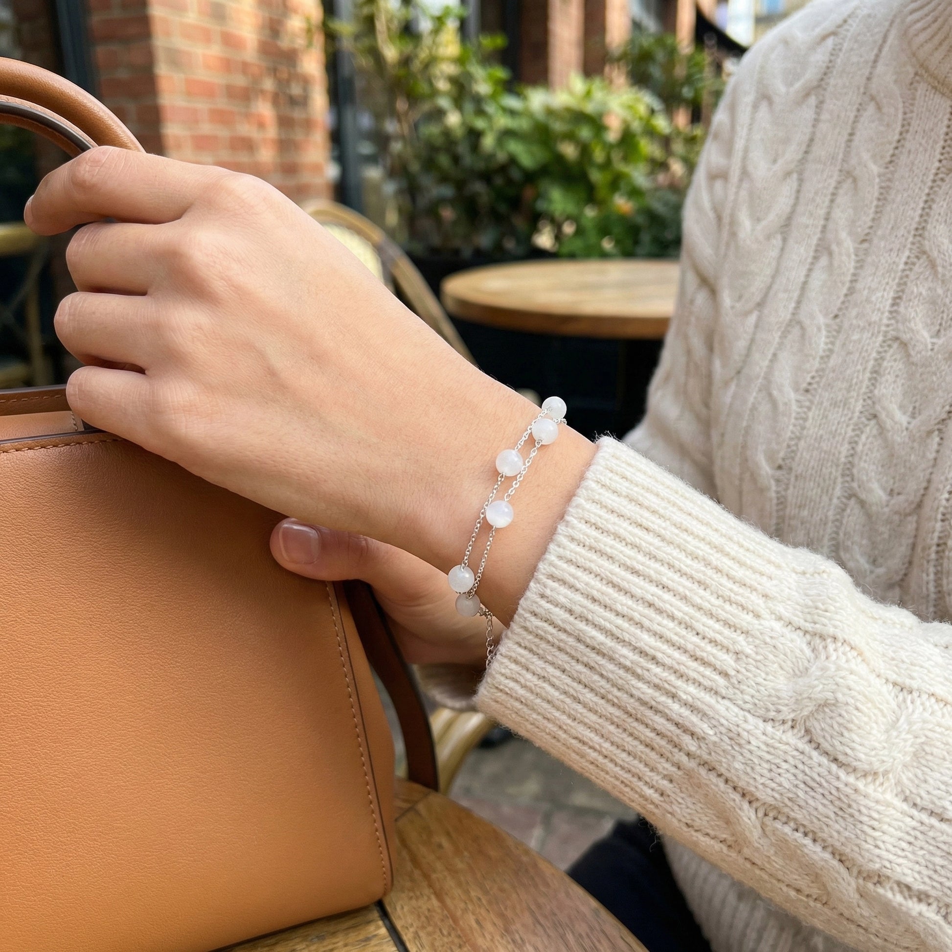 Person holding a brown leather bag with a blurred outdoor background