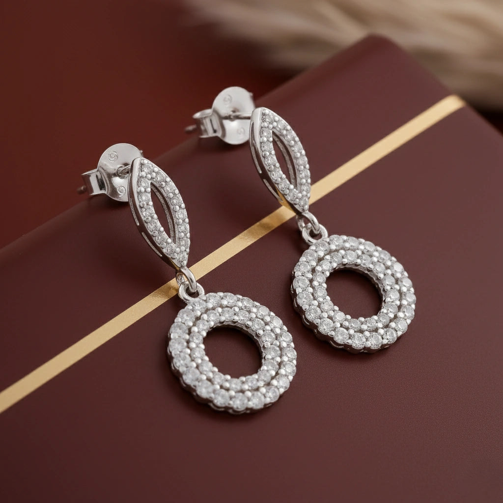 Silver earrings with circular design on a brown surface