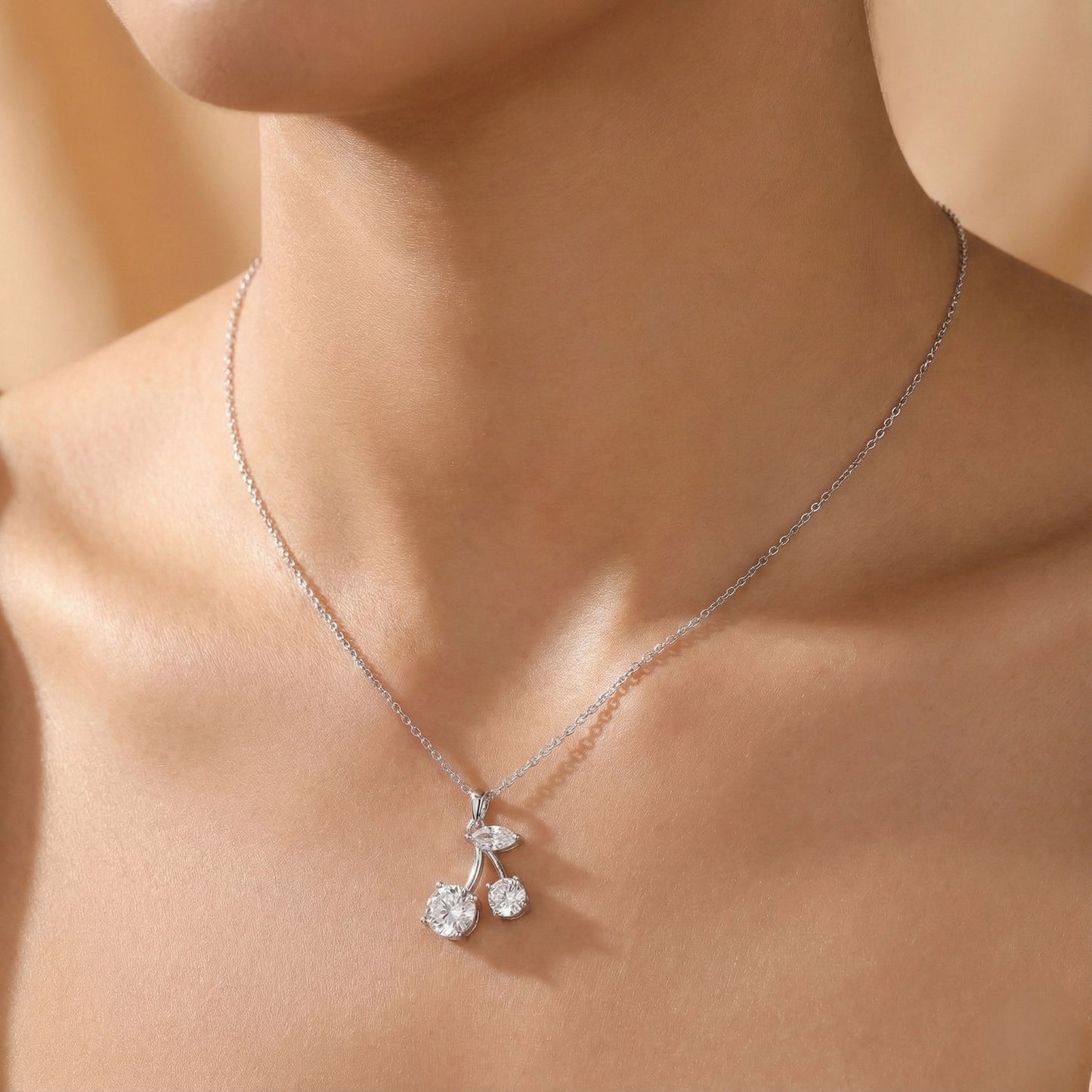 Silver necklace with a cherry pendant on a person's neck