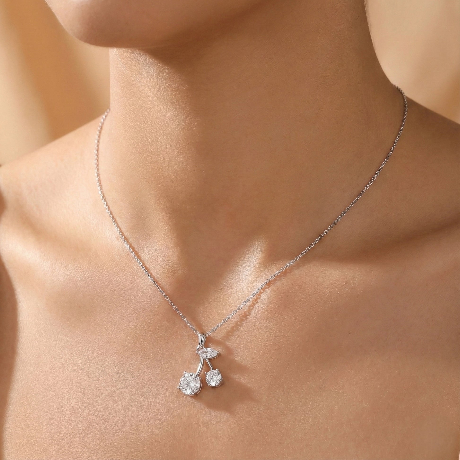 Silver necklace with a cherry pendant on a person's neck