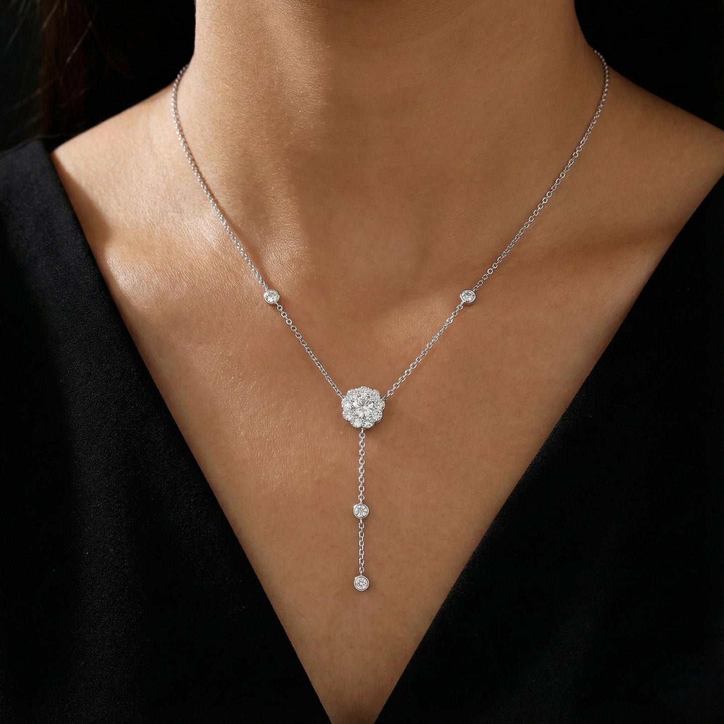 Silver necklace with a central pendant on a person wearing a black top.