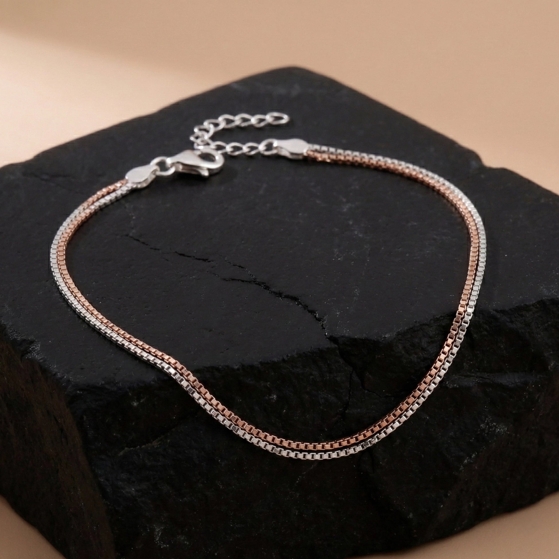 Two-toned bracelet on a dark stone surface with a beige background