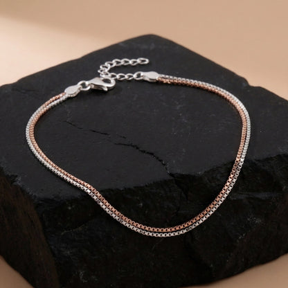 Two-toned bracelet on a dark stone surface with a beige background