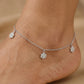 Silver anklet with star-shaped charms on a foot against a beige background