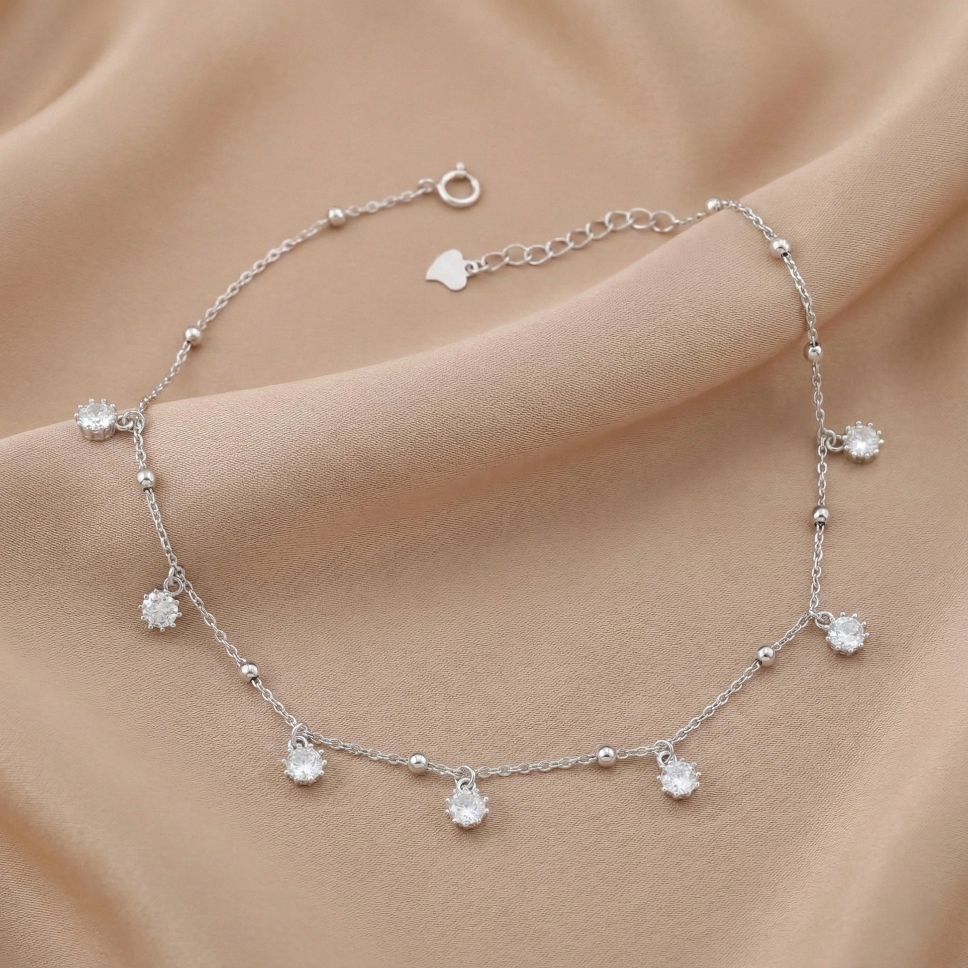 Silver bracelet with small crystals on a beige fabric background