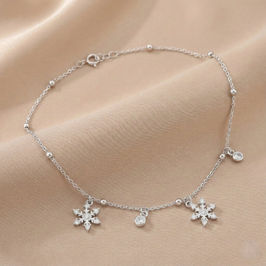 Silver bracelet with snowflake charms on a beige fabric background