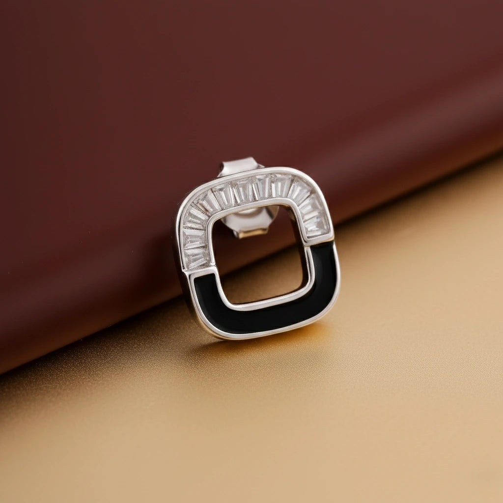 Silver ring with black and white gemstones on a brown surface