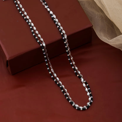Silver chain necklace on a red surface with a brown box in the background