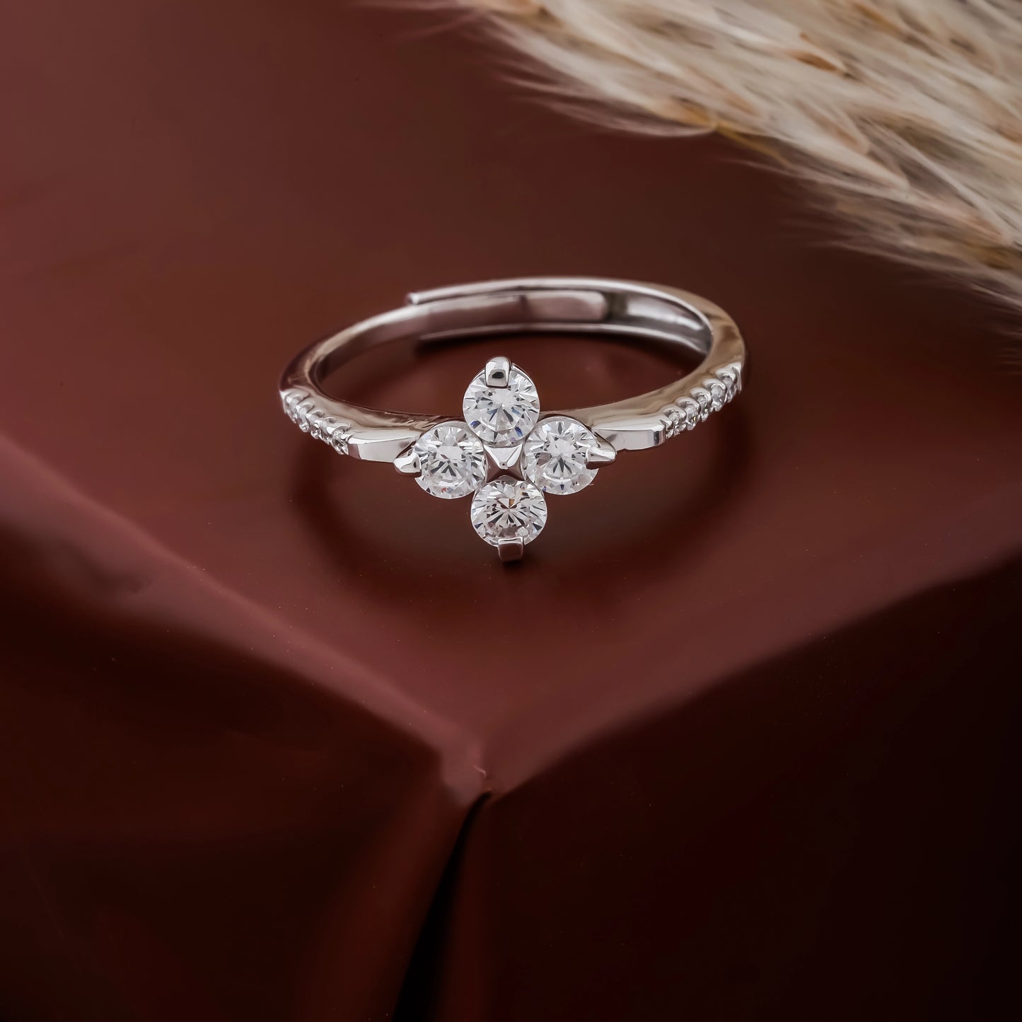 Silver ring with floral design and diamonds on a brown fabric background
