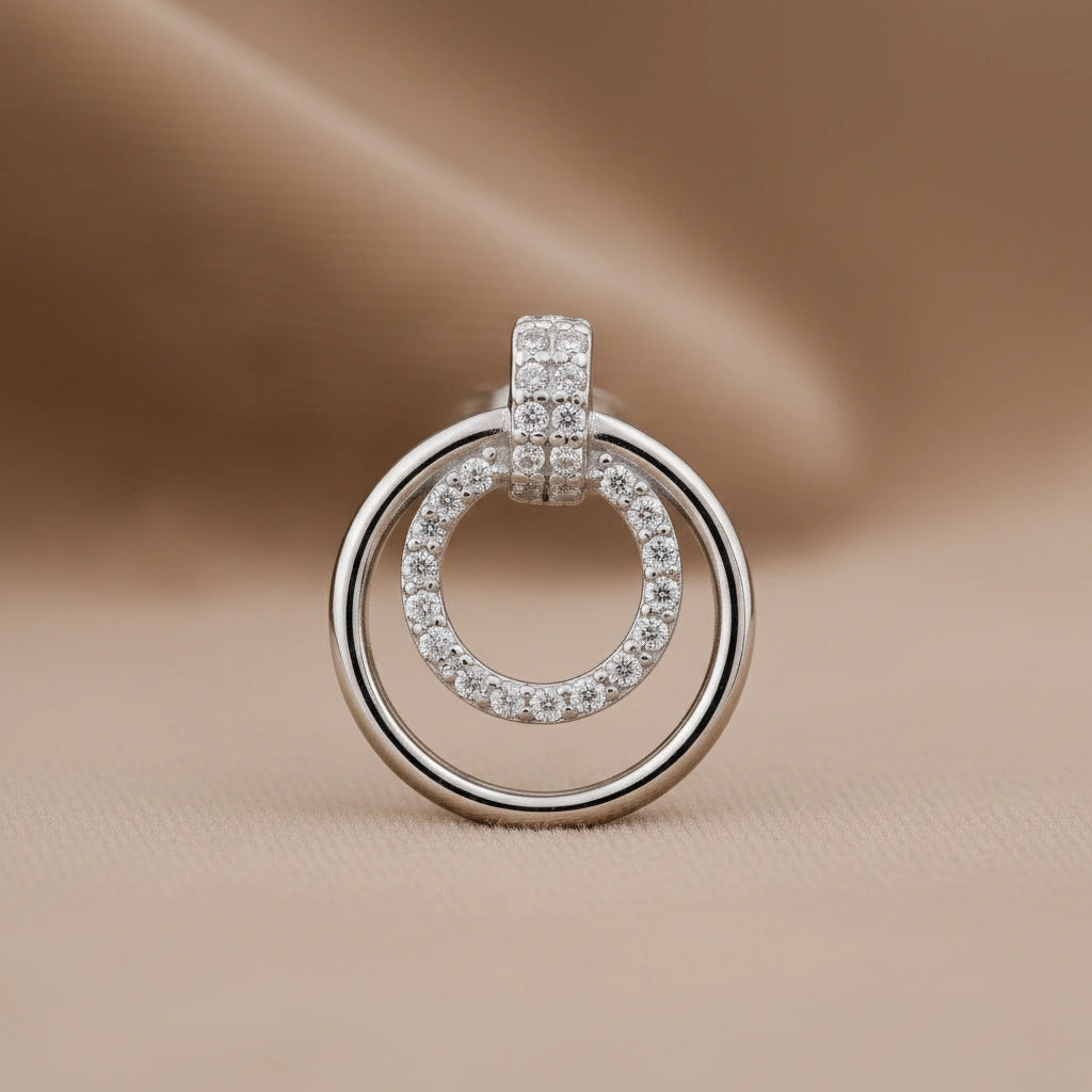 Silver ring-shaped earring with embedded stones on a beige background