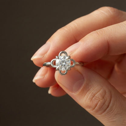 Silver ring with a diamond held in a hand against a dark background