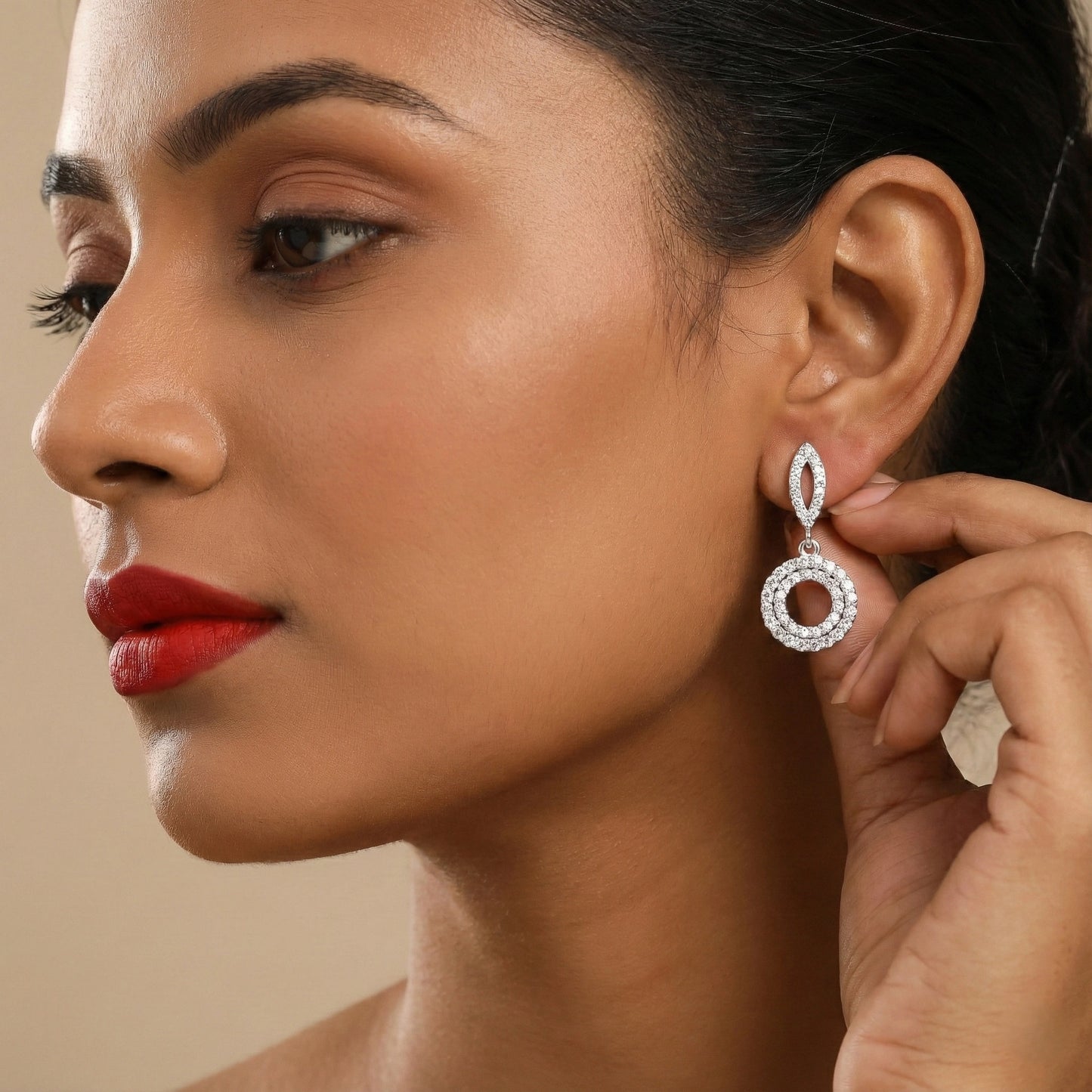 Close-up of a woman wearing a silver earring with a beige background