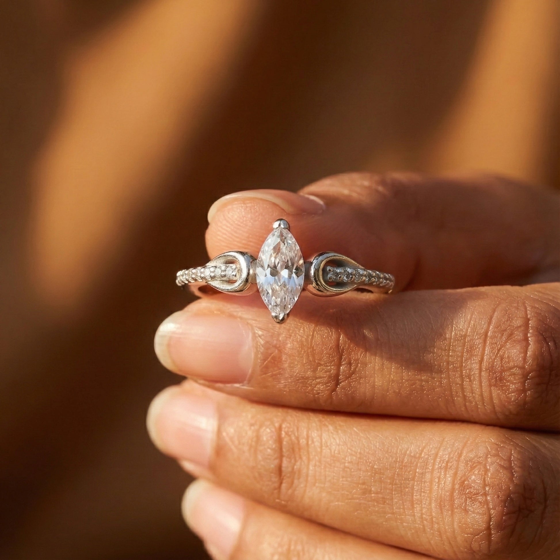 Diamond ring held between fingers with a blurred background