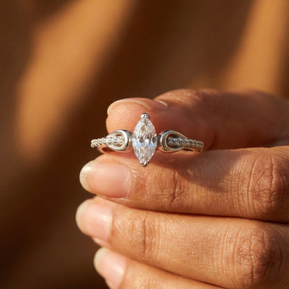 Diamond ring held between fingers with a blurred background