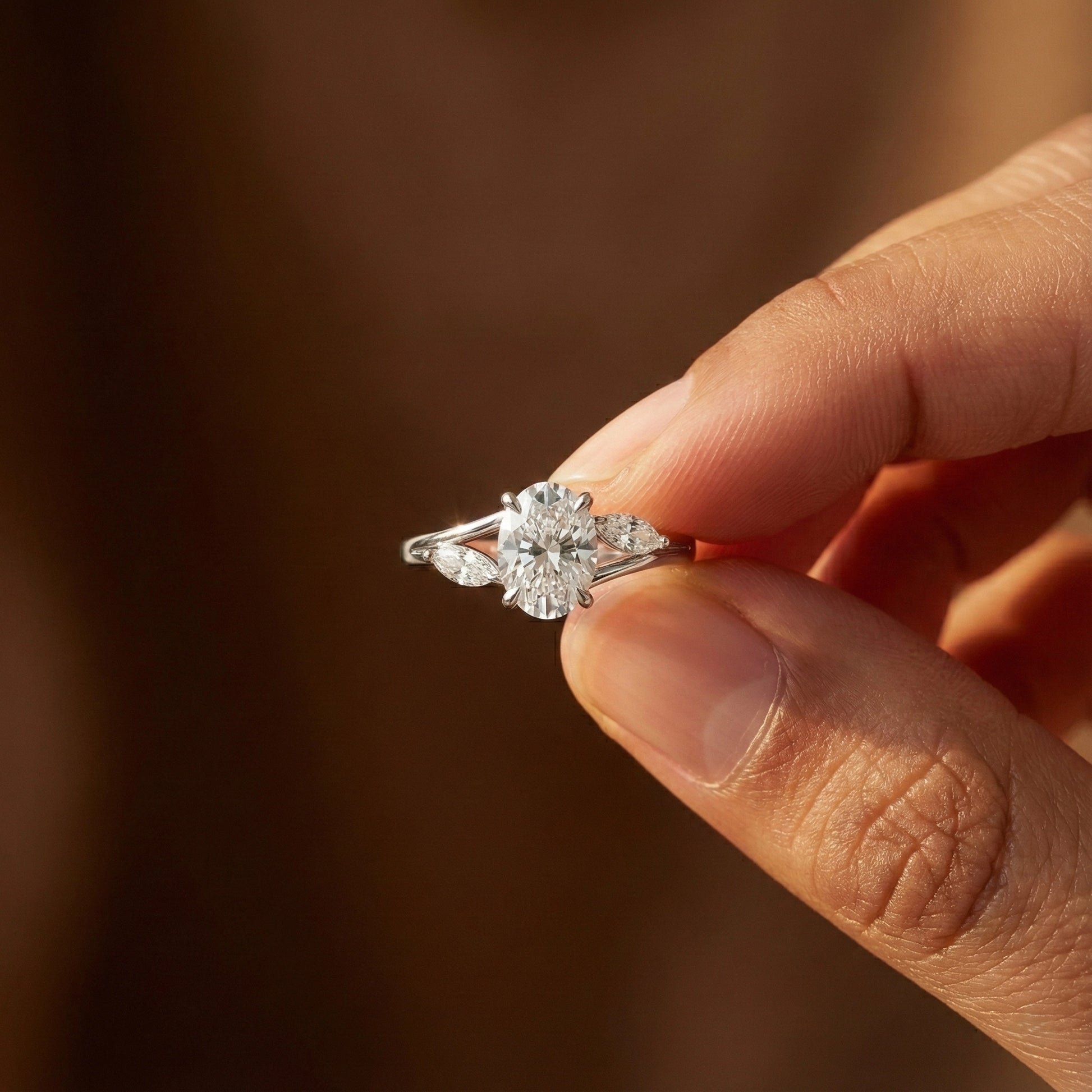 Diamond ring held between fingers against a blurred background