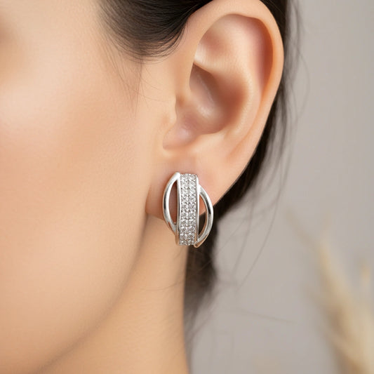Silver hoop earring worn by a person with a neutral background