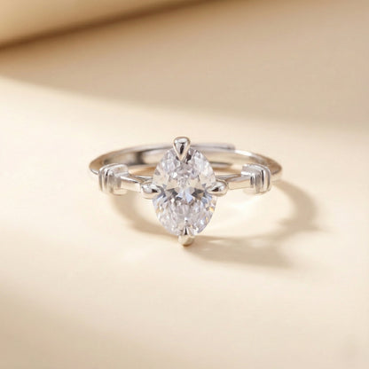 Silver ring with a pear-shaped diamond on a beige background