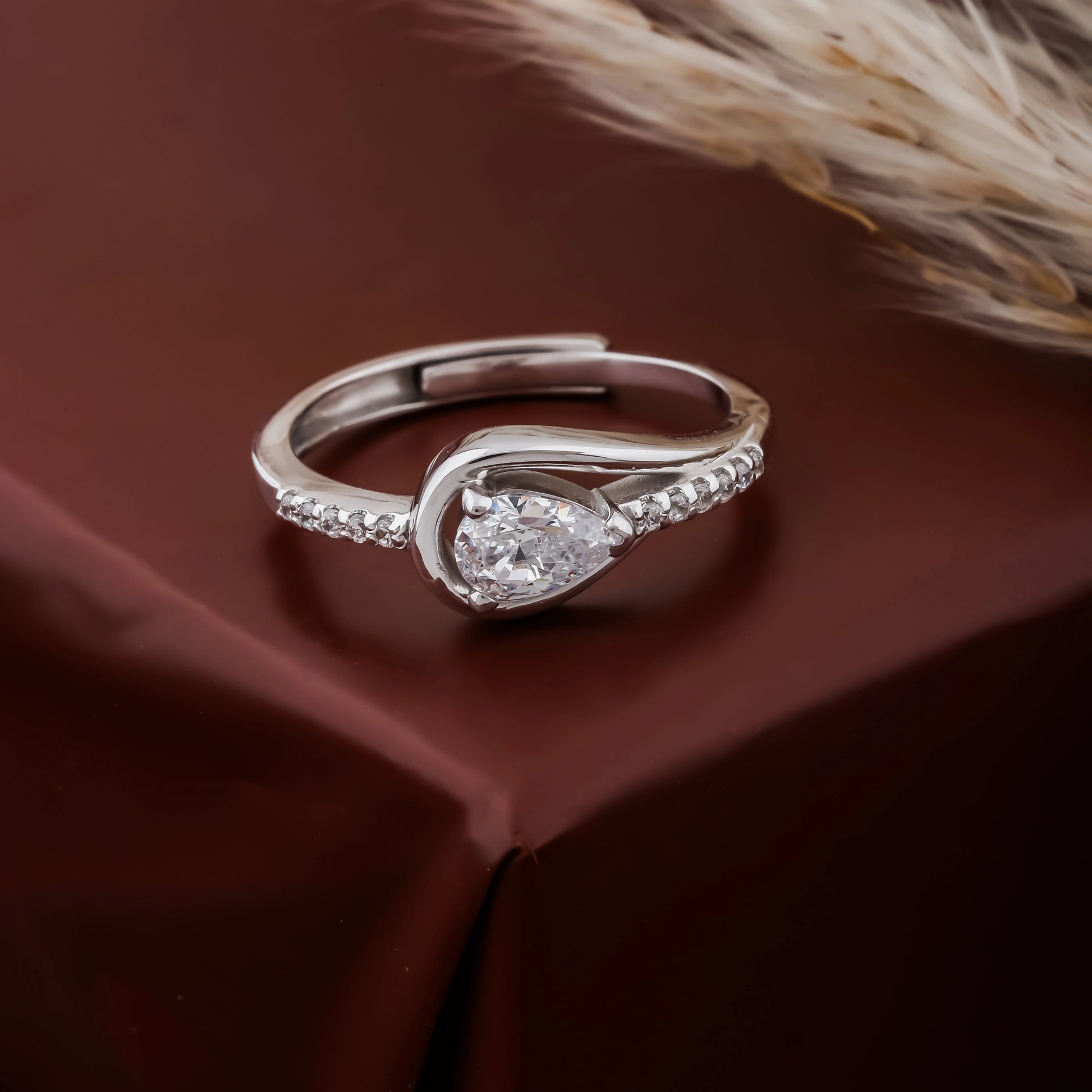 Silver ring with a pear-shaped diamond on a brown fabric background