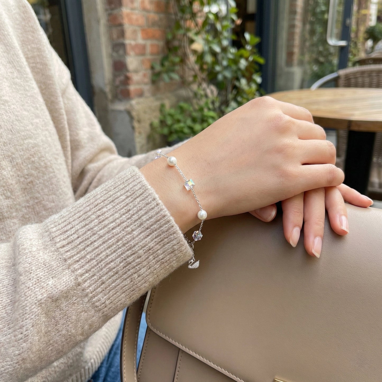 Hand wearing a bracelet with a blurred outdoor background