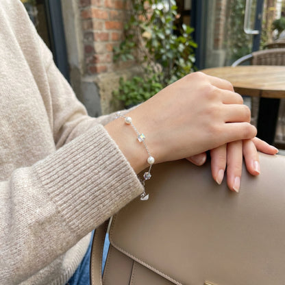 Hand wearing a bracelet with a blurred outdoor background