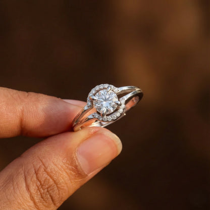 Diamond ring held between fingers against a blurred brown background