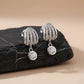 Silver earrings with clear stones on a black stone surface