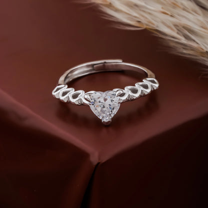 Silver ring with a heart-shaped diamond on a brown fabric background