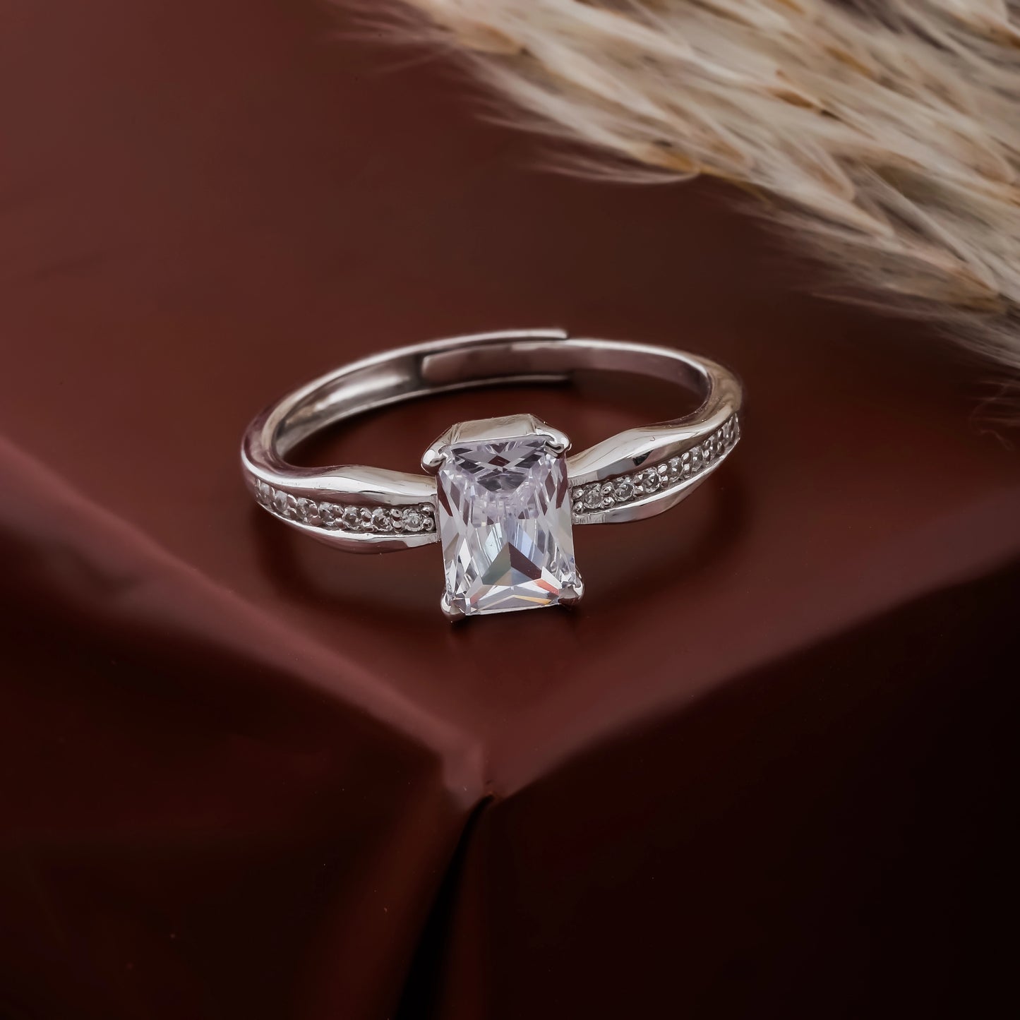 Silver ring with a rectangular diamond on a brown fabric background