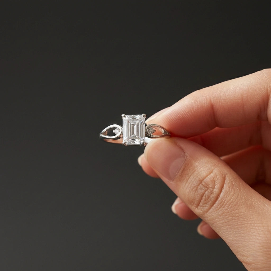 Diamond ring held between fingers against a black background
