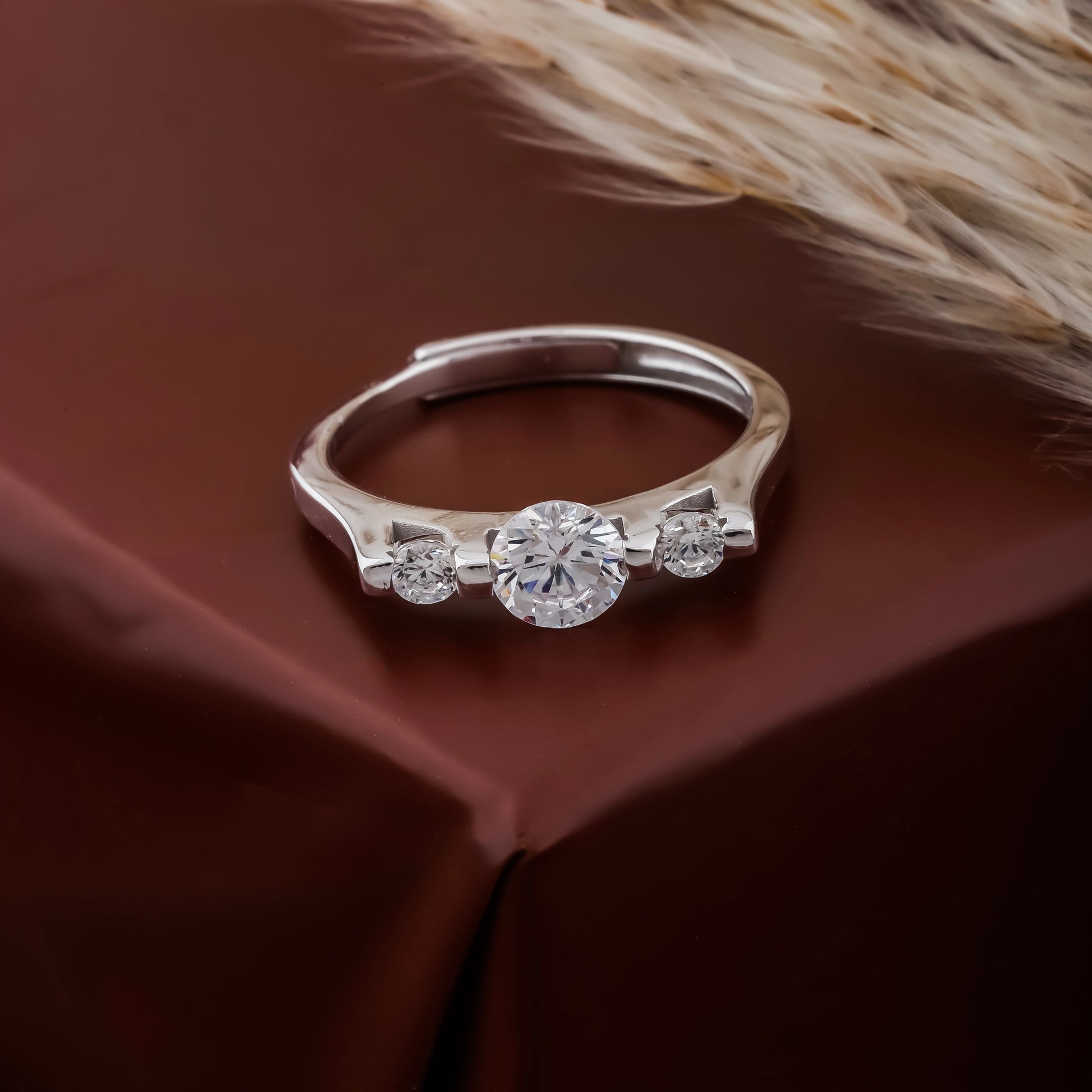 Silver ring with three diamonds on a brown fabric background