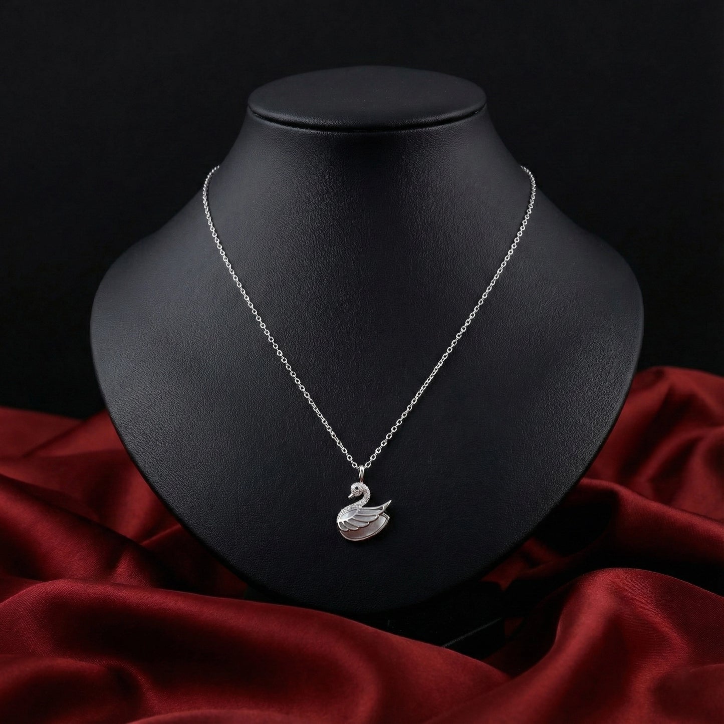Silver necklace with a swan pendant on a black mannequin bust against a dark background.