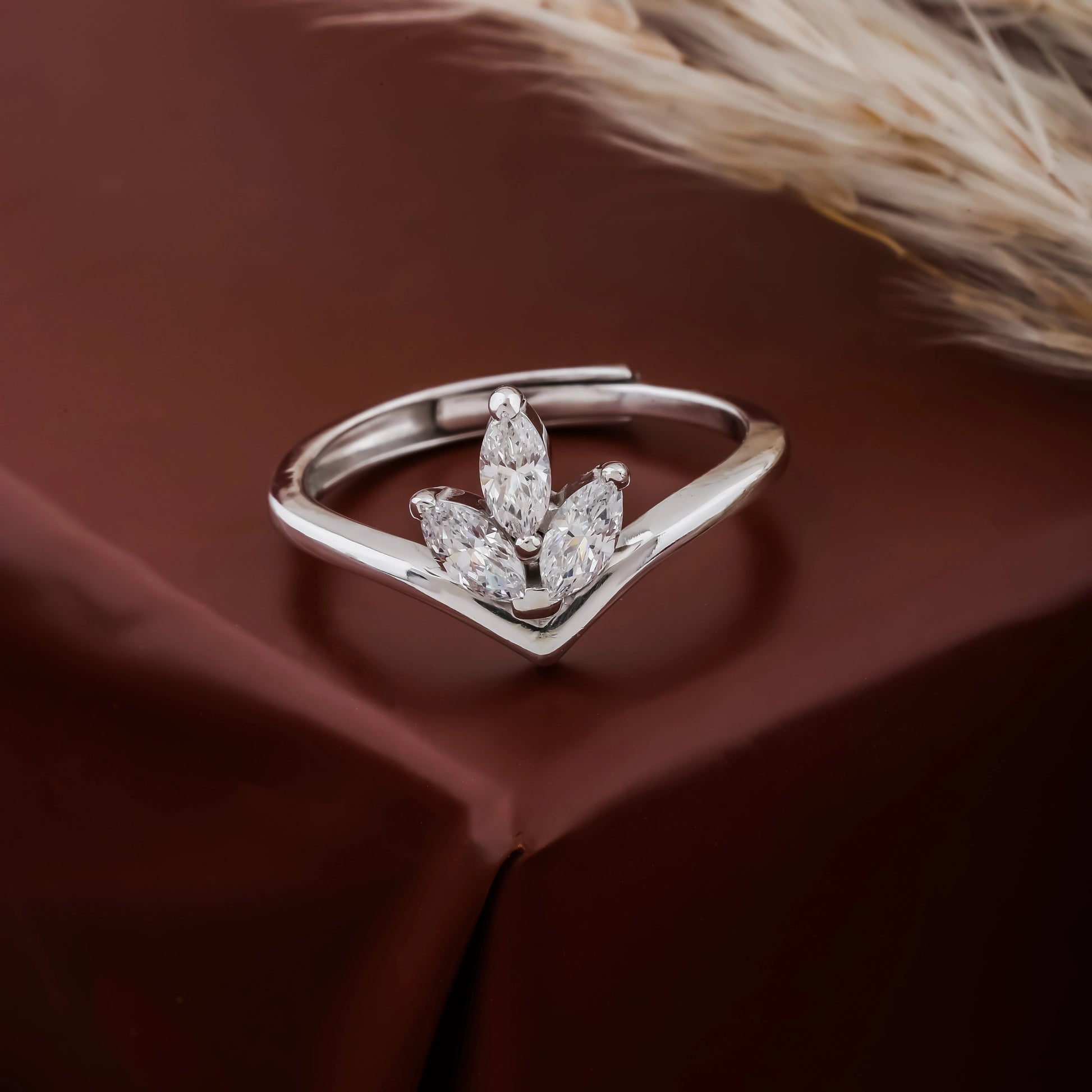 Silver ring with marquise-shaped diamonds on a brown fabric background