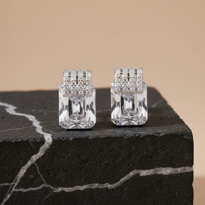 Pair of crystal earrings on a dark stone surface with a beige background