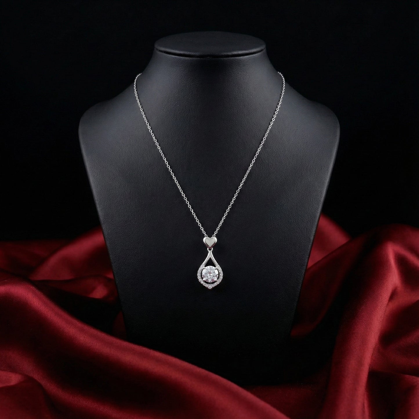 Silver necklace with a heart-shaped pendant on a black mannequin bust against a dark background.