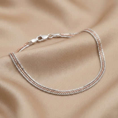 Two-layered silver bracelet on a beige fabric background